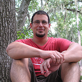 Portrait of Gerardo Celis sitting with trees in the background.