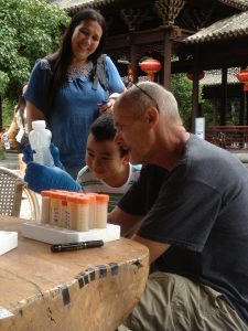 Researcher Paul Dijkstra in China showing child water sample from hot springs.