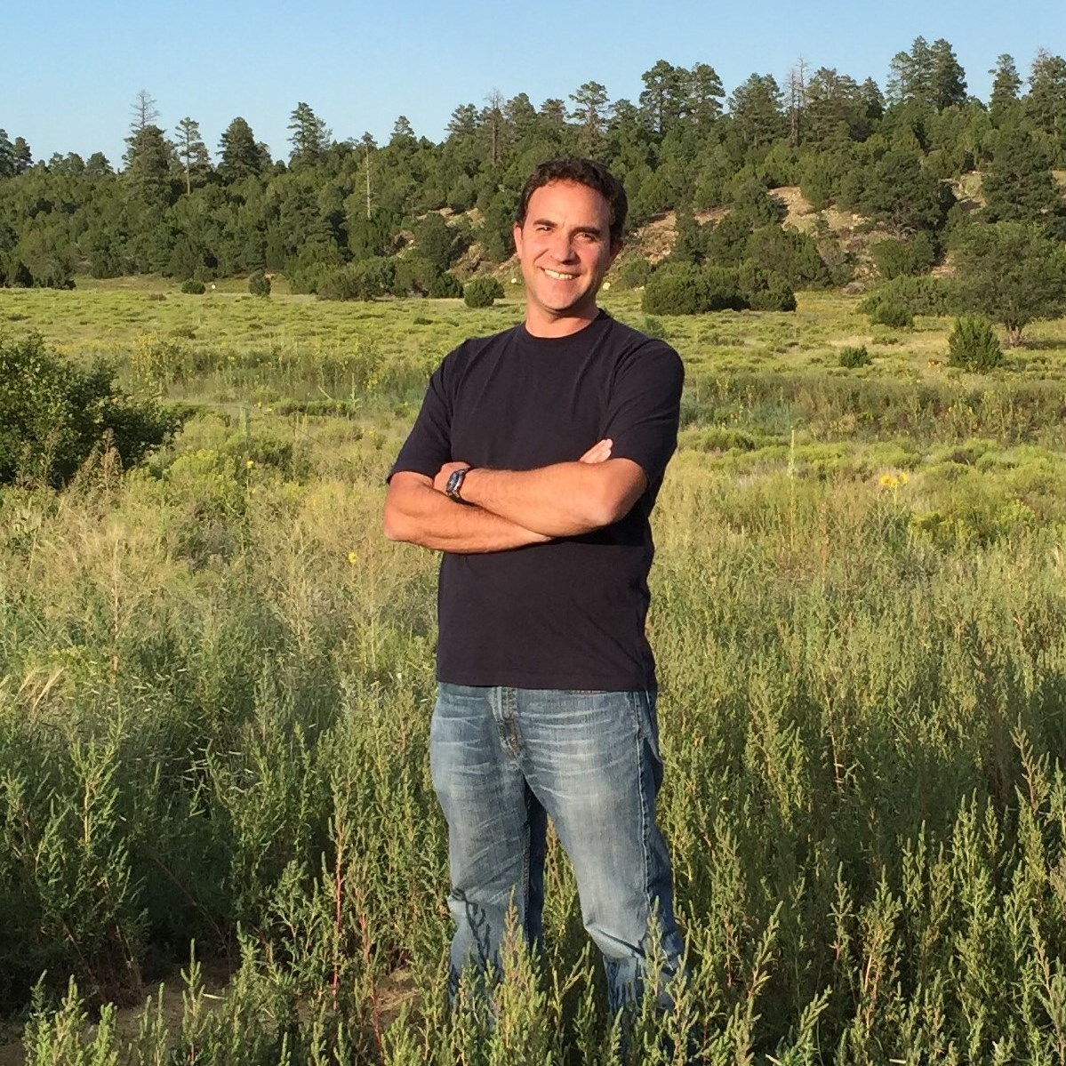 Portrait of César Plaza standing in clearing in forest.