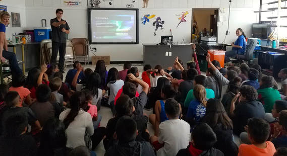 Fifth graders seated on the floor of the Killip STEM Lab listening to visiting scientists