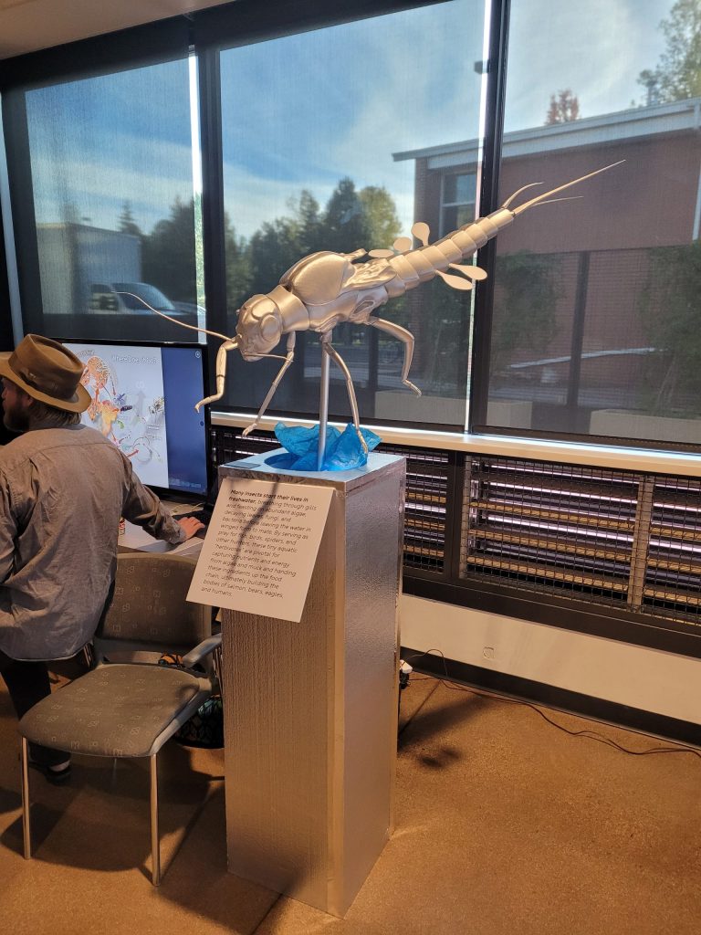 A silver insect sculpture on a plinth by the windows