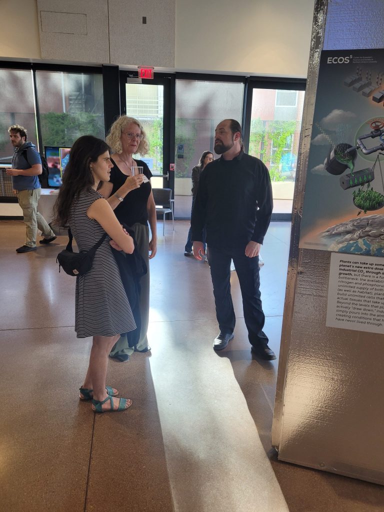 Victor Leshyk with guests beside an art panel